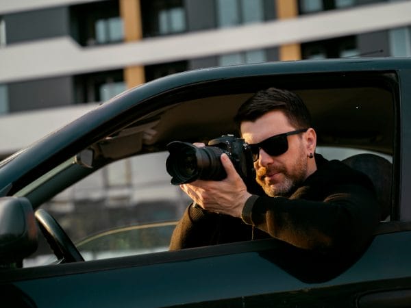 L'immagine mostra un investigatore privato che sta facendo una foto.